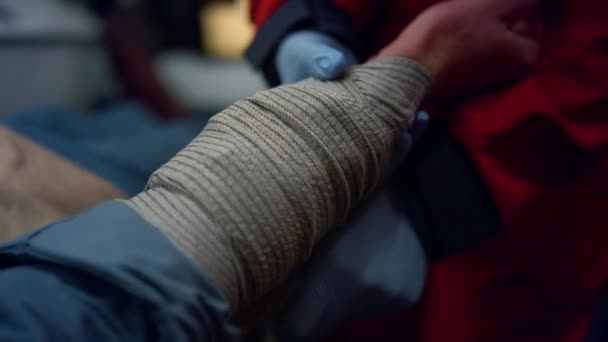 Primo piano ambulanza paramedico in guanti avvolgente mano paziente con bendaggio elastico — Video Stock