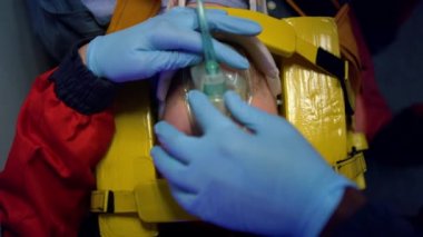 Sağlık görevlileri ilk yardım ekibine yardım ettiklerini kanıtlıyor. Doktorlar hastaya oksijen maskesi takıyor.