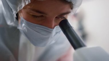 Laboratuvarda mikroskoba bakan bir bilim adamı. Araştırmacı örnekleri test ediyor
