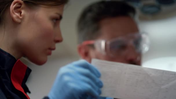 Πορτρέτο των σοβαρών παραϊατρικών εξετάζοντας ηλεκτροκαρδιογράφημα γραφήματα σε χαρτί — Αρχείο Βίντεο
