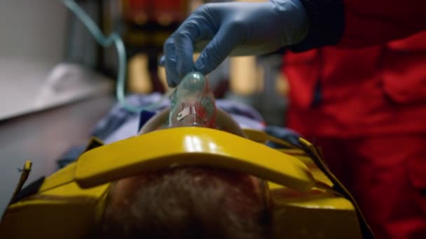 Mano paramédica en guante con máscara de oxígeno en la cara del paciente en el coche de emergencia — Vídeo de stock
