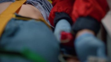 Sağlık çalışanı hastaya nabız oksimetresi uyguluyor. Kurban sedyelerde yatıyor.
