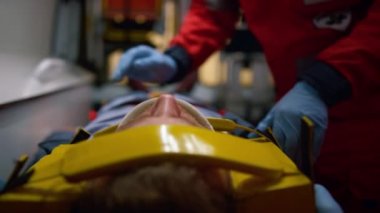Eldivenli ambulans ambulans ambulans arabasındaki sedyelerle hastayı muayene ediyor.