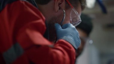 Acil servis doktoru steteskopu çıkarıyor. Sağlık görevlileri gece vardiyasında çalışıyor. 