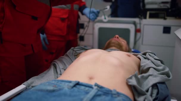 Paramedics rescuing patient in ambulance. Doctors applying holter monitor on man — Stock Video