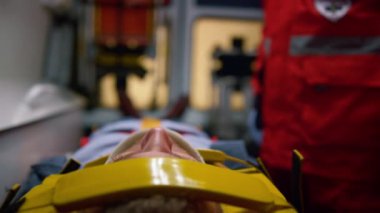 Ambulans arabasında sedyede yatan bir adam. Boyunluk takan erkek hasta.