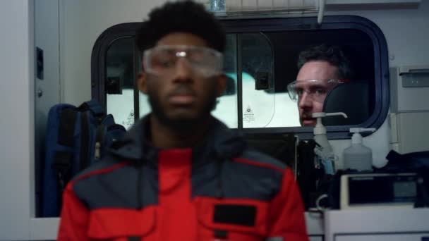 Multietniskt medicinskt team gör för nödsamtal i ambulans van — Stockvideo