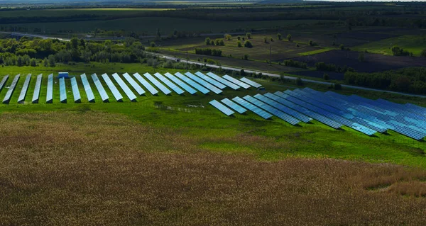 Blaue Sonnenkollektoren aus der Luft. Solarbatteriefarm auf der grünen Wiese. — Stockfoto
