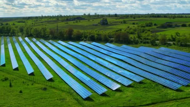 Drone schoot blauwe zonnepanelen rijen in groen veld. Ecologische elektrische generatoren — Stockvideo