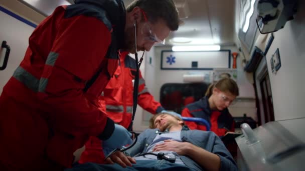 Paramédicos EMS medición de la presión arterial del hombre con tonómetro en vehículo de emergencia — Vídeos de Stock