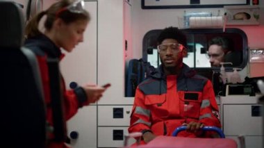 Doktorlar acil durum arabasıyla kurtarma için acele ediyorlar. Sağlık görevlileri araçta oturuyorlar.