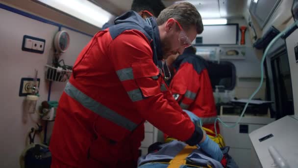 Médicos de emergencia realizando primeros auxilios ayudan al hombre en coche de emergencia — Vídeo de stock