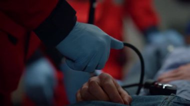 Eldivenli sağlık görevlileri hastanın tansiyonunu tonometreyle ölçüyor.
