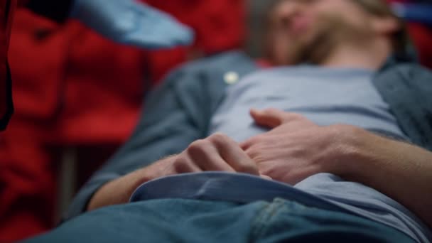 Pacient leží na nosítkách v sanitním voze. Unavený muž s bolestí břicha — Stock video