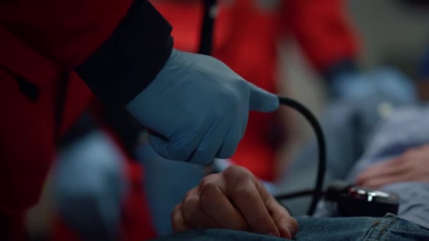 Mãos paramédicas nas luvas que medem a pressão arterial do paciente com tonômetro — Vídeo de Stock