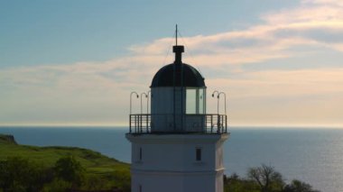 Kıyı şeridinde havadan deniz feneri manzarası ve arka planda güzel bulutlu bir gökyüzü..
