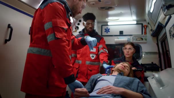 Multi paramédicos étnicos verificando pulso homem em macas em carro de emergência — Vídeo de Stock