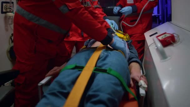 A mentősök elsősegélyt nyújtanak a betegnek a mentőautóban. Orvost vizsgáló férfi — Stock videók