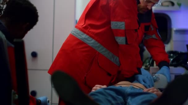 Blandad ras paramedicin som ger hjärtmassage till patienten i ambulans bil — Stockvideo