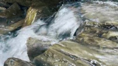 Taştan bir arazide dere. Dağ kayası deresi makrosu. Yakın çekim şeffaf akış