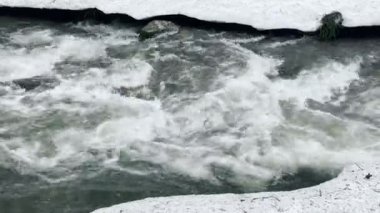 Kışın köpüklü nehir ve kar. Karlı arkaplanda hızlı akış.