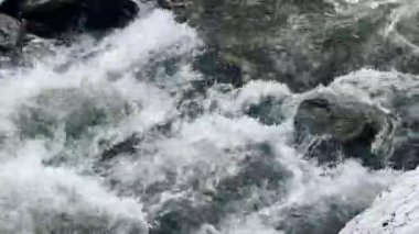 Nehirdeki akıntılar. Fırtınalı su akışında ıslak kayalar. Yakın çekim köpüklü nehir hızlı.