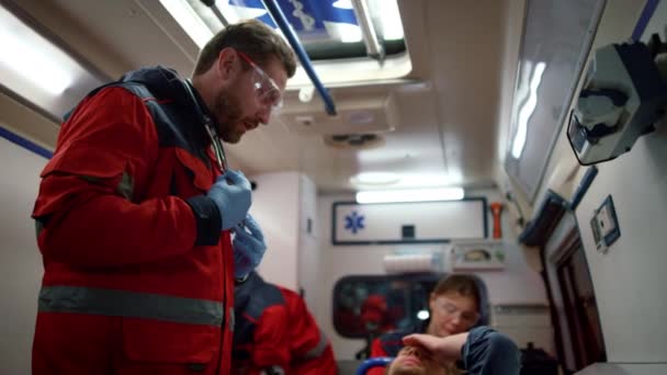 Médicos paramédicos examinando al paciente en camillas en coche de emergencia — Vídeos de Stock