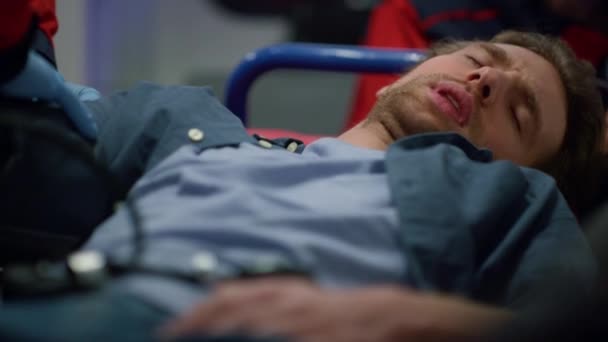 Muž ležící na nosítkách. Lékař dává tonometr na rameno pacienta — Stock video