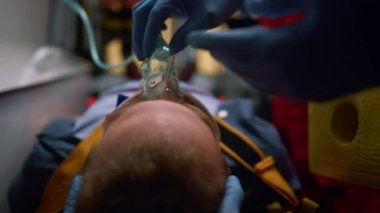 Sağlık görevlileri hastaya oksijen maskesi takıyor. Tıbbi asistanlar kurbanı kurtarıyor.