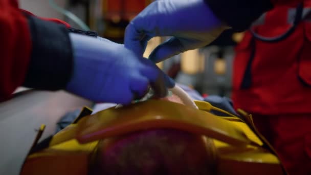 Equipe d'ambulanciers en gants prodiguant les premiers soins au patient en ambulance — Video