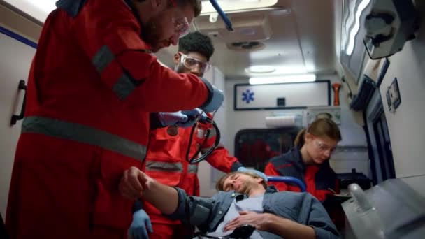 Medische artsen zorgen voor slachtoffer op brancards in ambulance auto — Stockvideo