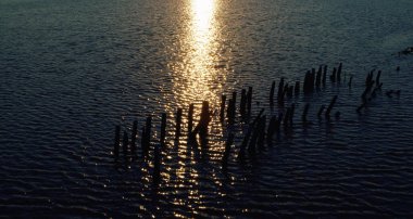 Sakin deniz yüzeyi yaz akşamı deniz manzaralı parlak altın gün batımını yansıtıyor.