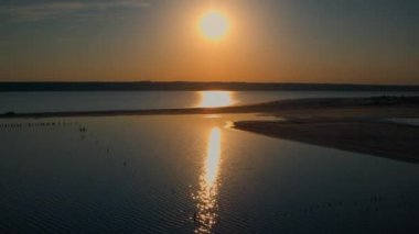 Romantik altın günbatımında drone deniz plajı. Küçük deniz dalgaları kumsala vuruyor.