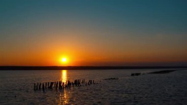 Panoramik deniz manzarası ve arka planda sakin sakin bir plaj. Akşam üstü gün batımı.