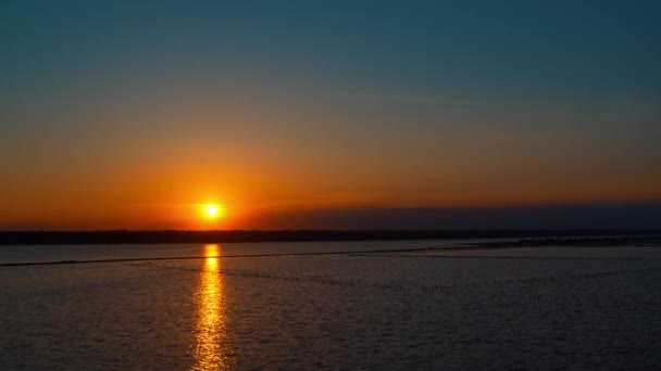 Panoramiczny widok na morze z dramatycznym złotym zachodem słońca. Spokojna plaża w tle. — Wideo stockowe
