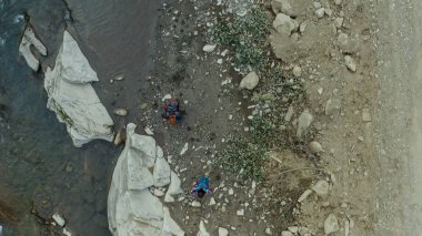 People walking mountain river hiking rocky bank enjoying adventure nature trip