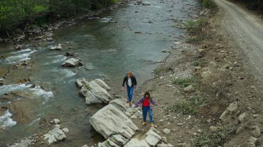Hikers walking river aerial view close mountain road among green forest trees