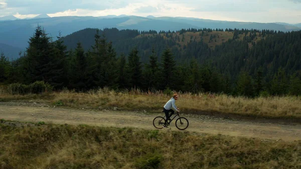 Ciclismo de montaña vista drone contra impresionantes colinas de abeto bosque disfrutando del tiempo — Foto de Stock