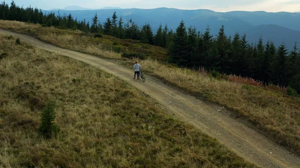 Aerial view mountain biking on hilly grassy road against blue sky enjoying — Φωτογραφία Αρχείου