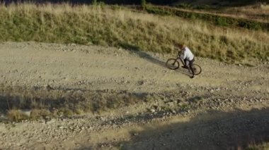 Mountain bike riding drone view rocky grassy path warm sunny summer day vacation