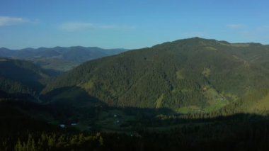 Aerial mountain valley village view with charming green rocky peaks blue sky