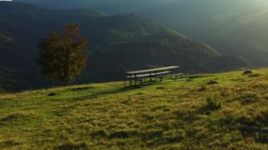 Bench green mountains nobody sit against impressive rocky landscape sunlights