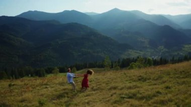 Aerial mountains couple dancing against stunning hills panorama sunny sky view