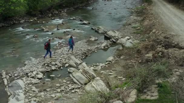 Hikers crossing river drone view cloudy spring day looking adventure vacation — Wideo stockowe