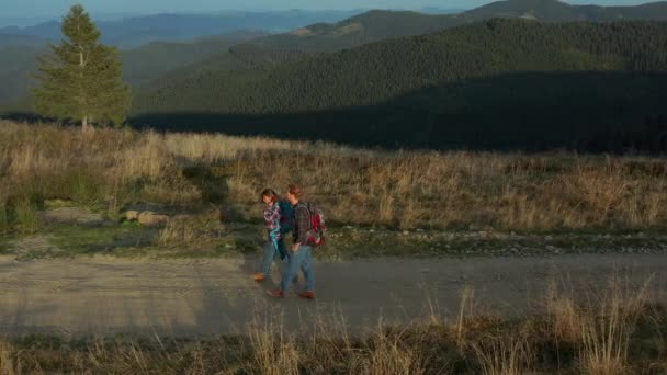 Drone tourists backpacks walking mountains path talking against green hills — Stok video