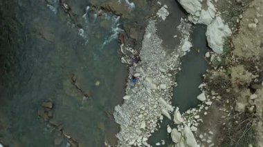 Couple walking rocky river shore looking around enjoying warm summer cloudy day