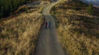 Couple trekking forest road aerial view walking among yellow grass warm day