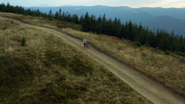 공중에서 보면 푸른 하늘을 배경으로 언덕 이 많은 풀밭 길에서 자전거를 타고 즐기고 있다 — 비디오