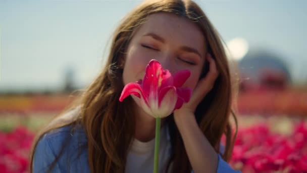 예쁜 아가씨가 꽃을 좋아하네. 꽃밭에서 눈을 감고 있는 아름다운 여인. — 비디오