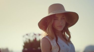 Sensual blonde woman in sunhat looking at camera in bright summer day outside.
